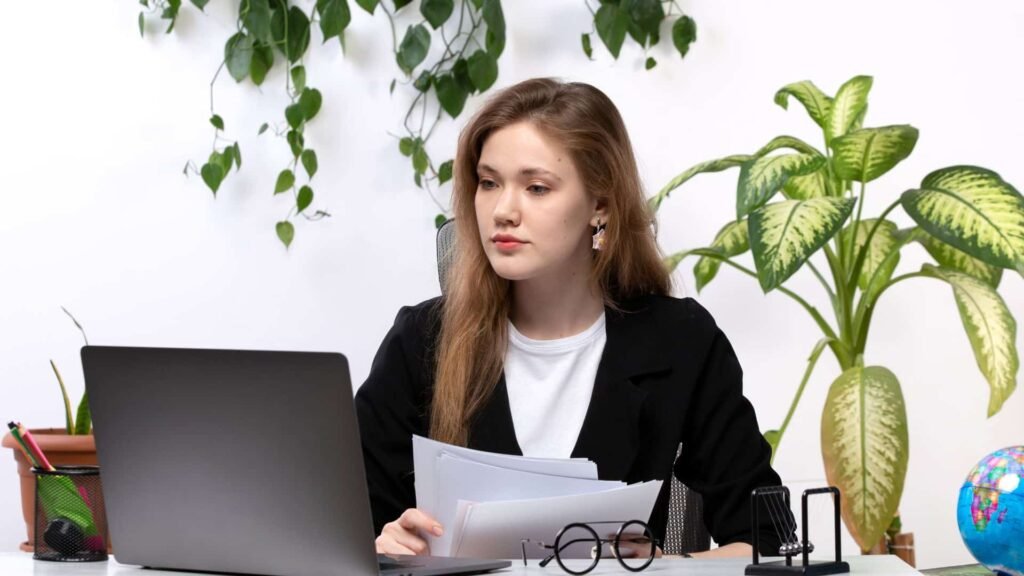 A female advocate working on her laptop in a professional office setting, reviewing legal documents and preparing case notes for the client she got from their website.